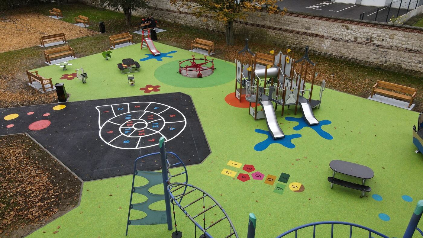 Aire de jeux réalisée par Arena Jeux vue du ciel — sols EPDM colorés, structures et marelles